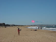 niña jugando con una cometa en la playa brava