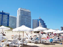 sombrillas en la playa mansa con importantes hoteles de fondo